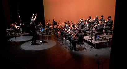 “Concierto de big band: director y sección de metales en el escenario.”